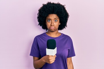 Young african american woman holding reporter microphone skeptic and nervous, frowning upset because of problem. negative person.