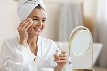 Positive beautiful lady hydrating skin, using cotton pads
