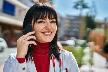 Young brunette woman wearing doctor uniform speaking on the phone at the city