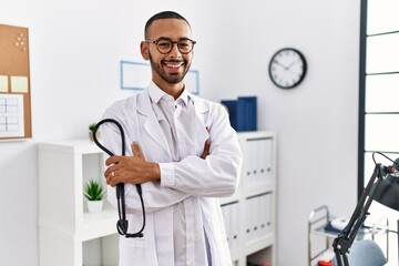 African american doctor man holding stethoscope at the clinic smiling with a happy and cool smile...