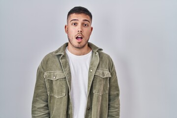 Young hispanic man standing over isolated background afraid and shocked with surprise and amazed expression, fear and excited face.