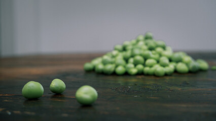Fresh peeled green pease on a brown wooden table with copy space. Still life of green peas in pods with pea shoots on wooden table