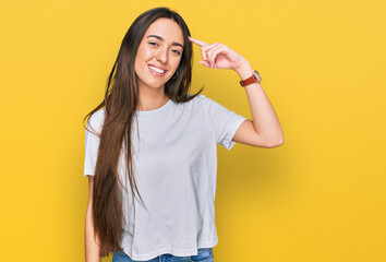 Young hispanic girl wearing casual white t shirt smiling pointing to head with one finger, great idea or thought, good memory