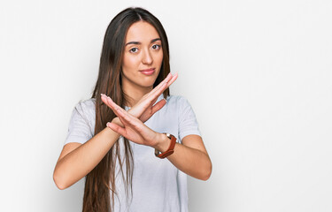 Young hispanic girl wearing casual white t shirt rejection expression crossing arms doing negative sign, angry face