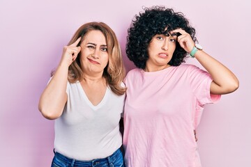 Middle east mother and daughter wearing casual clothes worried and stressed about a problem with hand on forehead, nervous and anxious for crisis