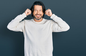 Middle age caucasian man wearing casual clothes smiling pulling ears with fingers, funny gesture....