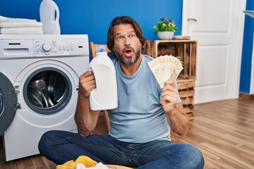 Handsome middle age man saving money of laundry detergent afraid and shocked with surprise and...