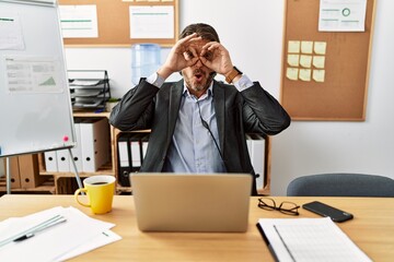 Handsome middle age man wearing call center agent headset at the office doing ok gesture like binoculars sticking tongue out, eyes looking through fingers. crazy expression.