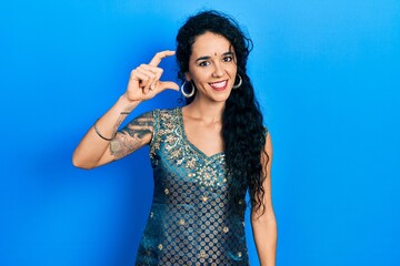 Young woman wearing bindi and traditional kurta dress smiling and confident gesturing with hand...