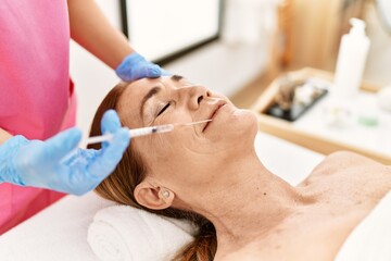 Obraz na płótnie Canvas Middle age caucasian woman having anti-aging face treatment at beauty center