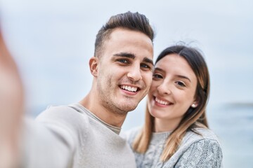 Fototapeta premium Man and woman couple hugging each other make selfie by camera at seaside