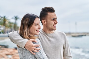 Obraz premium Man and woman couple smiling confident hugging each other at seaside