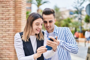 Man and woman couple using smartphone standing together at street