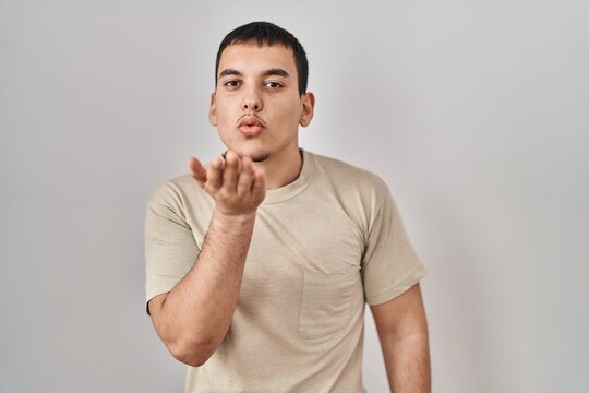 Young arab man wearing casual t shirt looking at the camera blowing a kiss with hand on air being lovely and sexy. love expression.