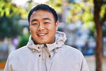 Young chinese man smiling confident standing at park