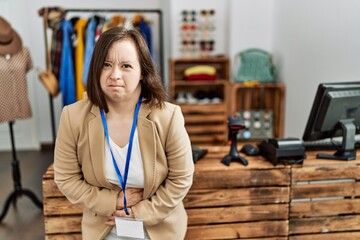 Young down syndrome woman working as manager at retail boutique with hand on stomach because...