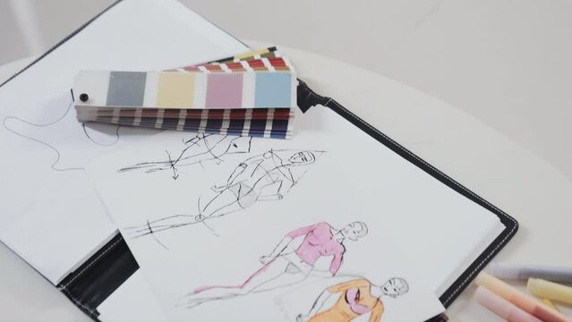 High angle view of glass of red wine, fashion sketches, paper and color palettes on worktable of designer