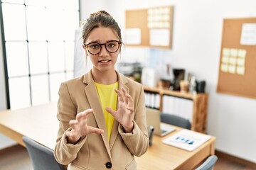 Young brunette teenager wearing business style at office disgusted expression, displeased and...