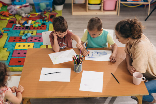 kids with their teacher drawing in kindergarden