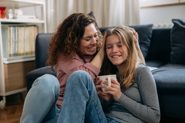 happy mother and daughter feeling carefree, sitting in living room