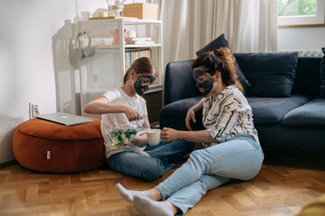 mother and daughter with cosmetic face mask enjoying time at home