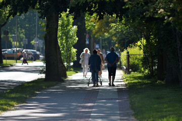 Obraz premium Two elder people walking in a park in Berlin-City on a warm and sunny spring day. A handicapped male walker with a 