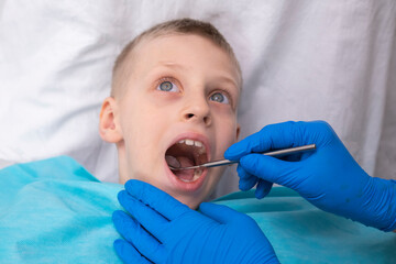 boy opens her mouth wide and pulls out long tongue. child shows his teeth soft palate and mouth to dentist. mouth is wide open, tongue is stuck out as far as possible, with clear view of tongue - obrazy, fototapety, plakaty