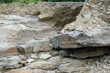 The rocky cliffs near the river have eroded over time and the water shows the natural color of the rock. Piles of stones scattered on the banks of the river.
