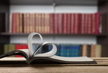 An open book forming a heart with two pages in the center, in the library. In the background are...