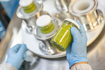 Pesto sauce Industrial process. High quality sauce production. Factory worker working on vacuum...