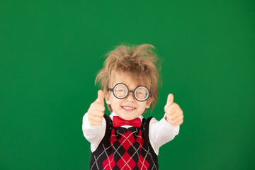 Happy child in class against green chalkboard