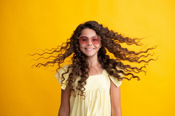 Teenager portrait with crazy movement hair. Young teen child with flowing hair. Brunette teen girl fluttering hair in motion, isolated on yellow background. Happy teenager.