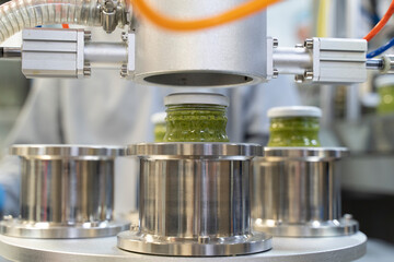 close up on Pesto sauce Industrial process. vacuum sealing machine for canned food. production of Pesto sauce. Vacuum Seamer for Cylindrical Cans of Rotary Type.