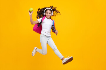 Back to school. Schoolgirl student in headphones with school bag backpack hold book on isolated studio background. School and education concept.