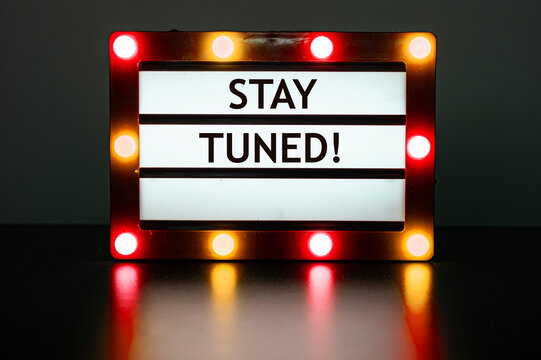 Lightbox with red and orange lights in dark room with words - stay tuned!