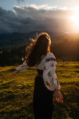 Ukrainian girl in Carpathians mountains in an embroidered shirt ( vyshyvanka ) from back on sunset. Stand with Ukraine
