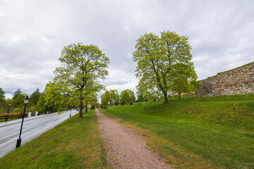 Fototapeta na wymiar Beautiful landscape view in Uppsala city downtown with high stone wall, trees and highway. Sweden.