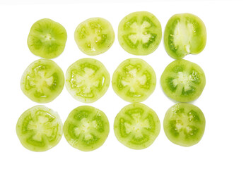 Green unripe tomatoes slices isolated on white background.