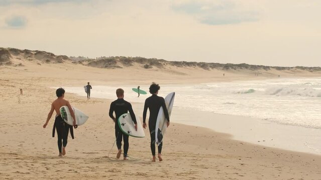 Unidentified surfers with surf board walk on the Baleal beach in Portugal.