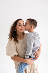 Naklejka premium Boy preschooler and mother smile and hug on gray background in photo studio