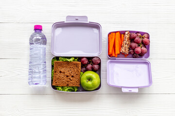Healthy food in purple lunch boxes. Sandwich and fruits for fast meal