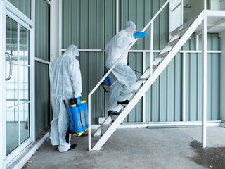Two cleaner man walking up stairs while holding sanitizer backpack in hygiene uniform suit before start cleaning service