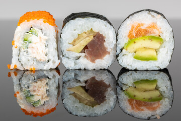 Set of three sushi rolls with salmon, tuna and avocado. Sushi with reflection. Traditional japanese food