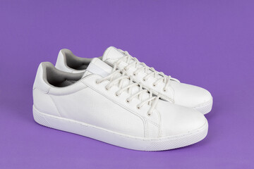 Pair of new white sneakers on purple background