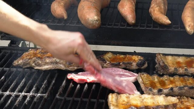 Chef cooking tasty ribs pork on a barbecue grill. Close up of delicious grilled pig cooked in BBQ of garden home at holiday vacations in Spain.