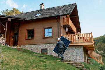 Man worker carrying solar panel for installing solar modul system on house.