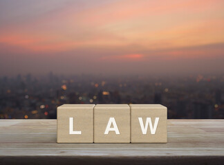 LAW letter on wood block cubes on wooden table over blur of cityscape on warm light sundown,...