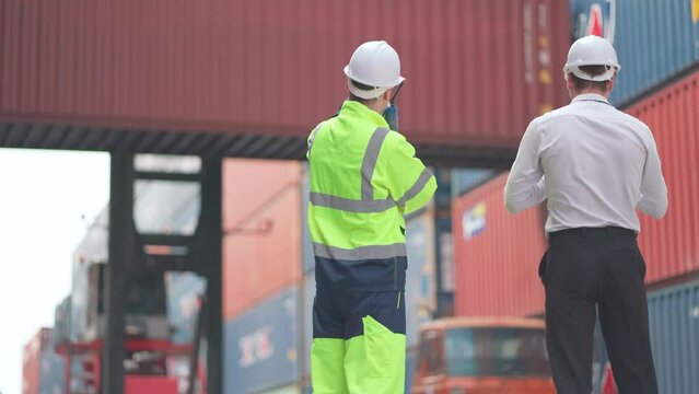Caucasian cargo container worker and manager discuss together and plan about tranportation in front of working crane carry container tank.