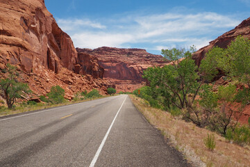 Asphalt US road no. 128 in Utah leading into gorge of red sandstone. Scenic road in the Utah desert. Travelling in the American southwest. Very hot sunny day