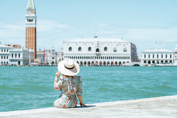 stylish woman in floral dress sitting on waterfront